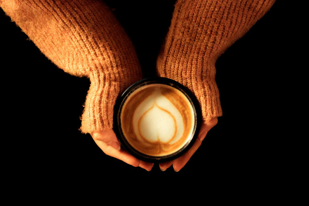 女人的手握着咖啡杯-黑色背景图片下载