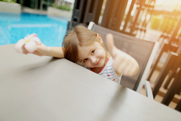 可爱的小女孩的肖像显示大拇指或喜欢在游泳池图片下载