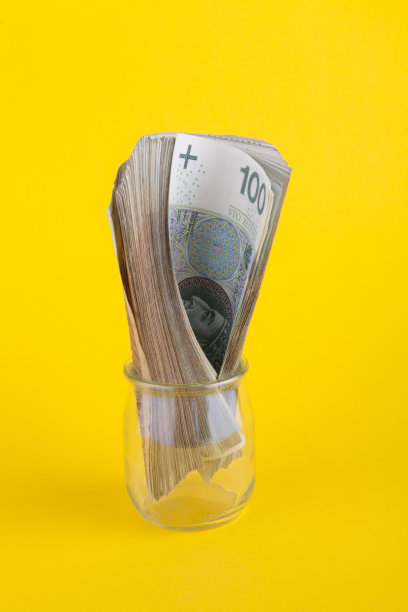 一卷波兰钞票放在一个黄色背景的小玻璃罐里图片下载