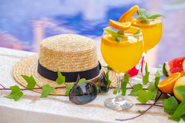 西瓜鲜榨果汁冰沙饮料玻璃与花，太阳镜，拖鞋和草帽的边界上的一个游泳池-假日热带概念图片下载