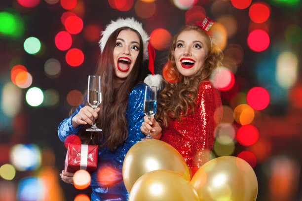 两个圣诞女性朋友。冬季时装女孩笑抽象散景闪闪发光的派对背景图片下载