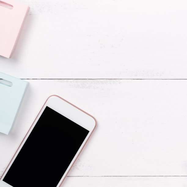 摘要网上购物、移动支付概念设计元素，彩色购物车和纸袋放在白色木质桌子背景上，俯视图，平铺图片下载