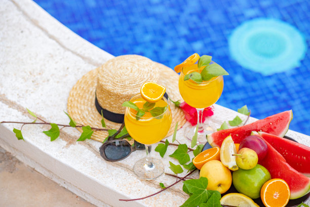 西瓜鲜榨果汁冰沙饮料玻璃与花，太阳镜，拖鞋和草帽的边界上的一个游泳池-假日热带概念图片下载