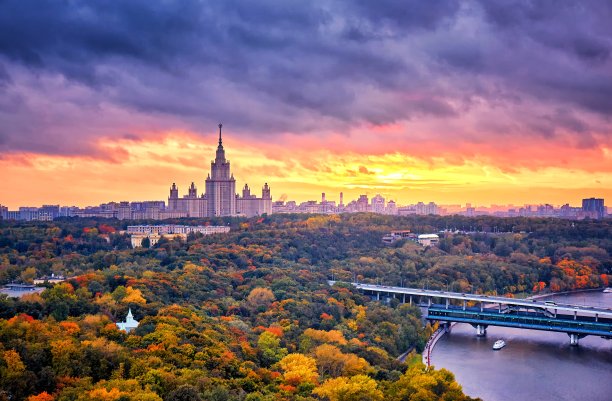 河流、公园、桥梁、船只和大城市秋季景观的河流、公园、桥梁、船只和大城市的全景日落云图片下载