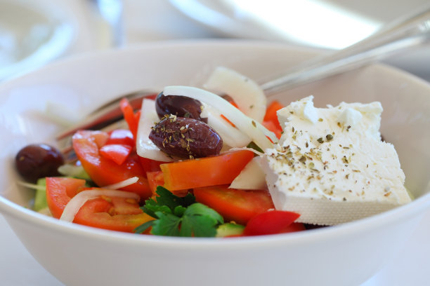 希腊沙拉配羊乳酪，橄榄和蔬菜在白色深盘。图片下载