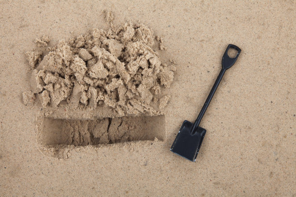 美丽独特的沙子和铲子在地上挖一个洞图片下载