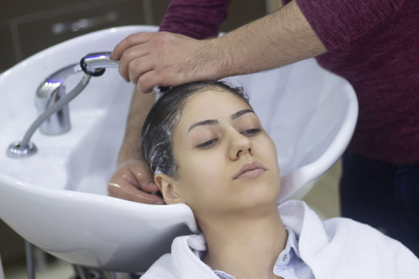 美发师在美发厅为一位年轻女士洗头图片下载