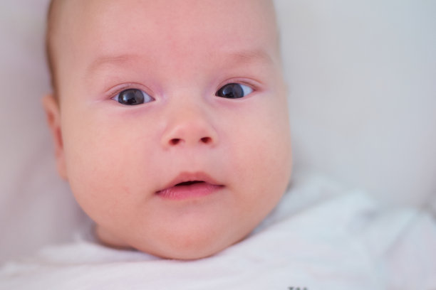 一个婴儿躺在床上，孩子看着相机图片下载