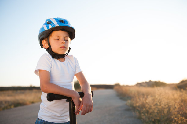 心理精神年轻运动员白种小孩在比赛开始前戴着头盔闭着眼睛骑着滑板车图片下载