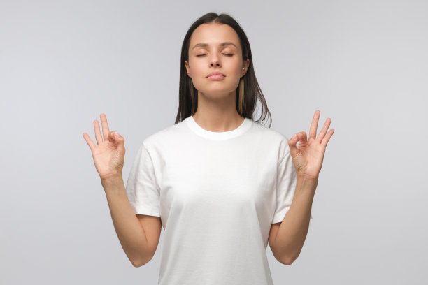 瑜伽和冥想概念。集中放松的女人闭着眼睛站着，在沉思中放松着，试图在孤立的灰色上找到平衡和和谐图片下载