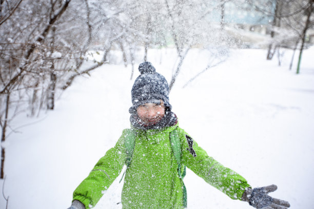 一个小男孩站在雪堆里图片下载