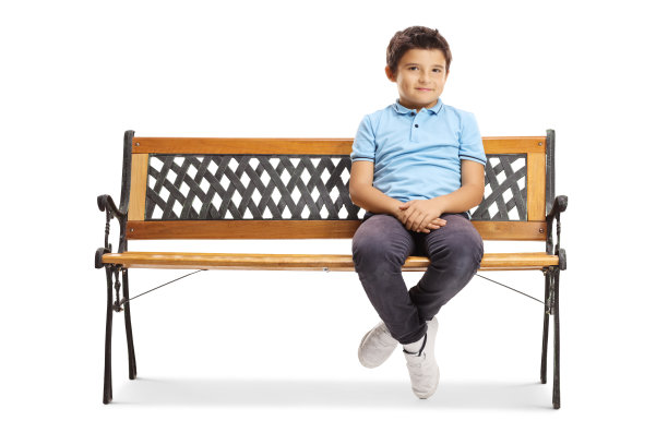 微笑的小男孩坐在长椅上看着镜头图片下载