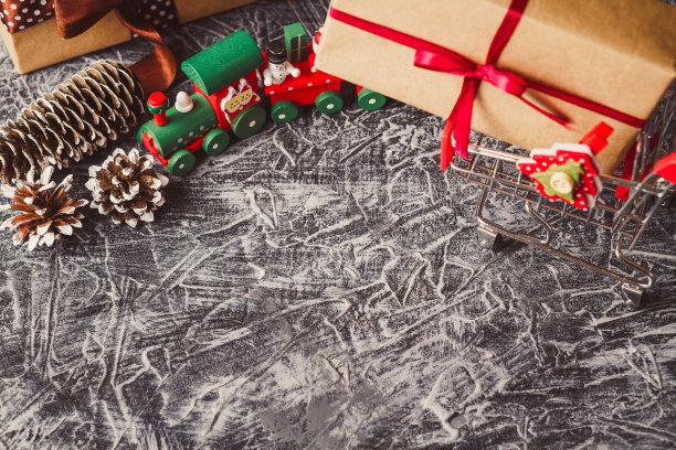 在水泥桌上放着装有礼物的购物车。圣诞和新年销售概念与copyspace。图片下载