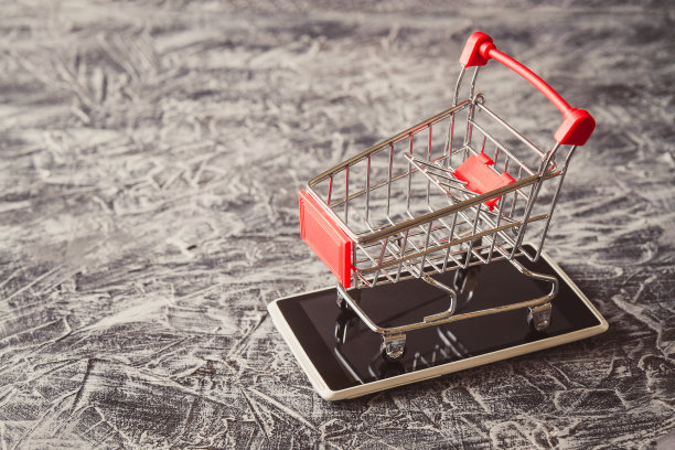 水泥桌上智能手机上的购物车的特写。电子商务和数字市场的概念与copyspace。图片下载
