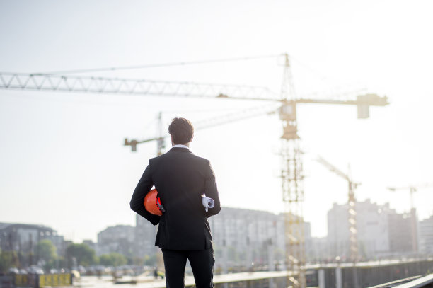 年轻的建筑工程师带着工程和安全帽图片下载