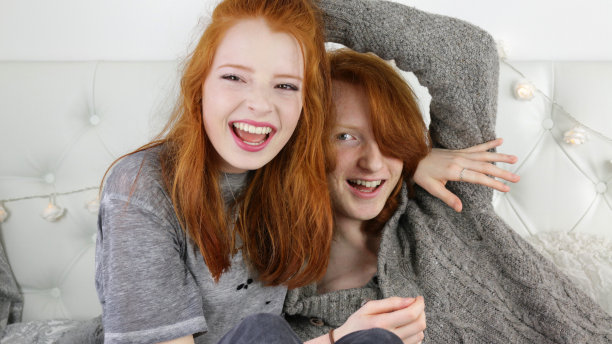 照片中，14 / 15岁的红头发女孩，皮肤苍白，脸上有雀斑，坐在卧室里，旁边是她16 / 17岁的姜黄色头发的哥哥，看着镜头微笑，四处嬉戏，男孩被妹妹拥抱，而她对着镜头大笑图片下载