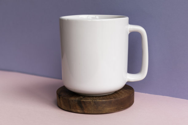 空白白色咖啡杯上的深色木制杯垫对蓝色和粉红色的背景-朴素的杯子模型模板零售图片下载