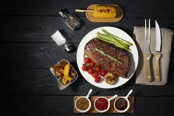 烤牛排配芦笋、西红柿、炸薯条和乡村土豆。三种不同的酱汁:番茄酱，芥末和烧烤在一个深色的木制背景，俯视图，水平照片图片下载