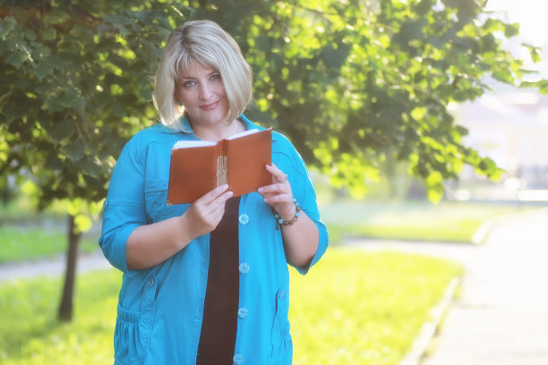 女人在公园的绿树与书图片下载