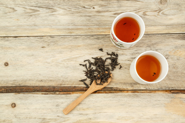 用勺子舀着印度红茶，用玻璃杯在木制背景上冲泡。从上往下看图片下载