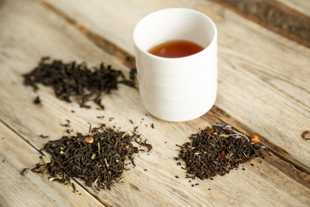 不同品种的天然茶在勺子和冲泡在一个木制背景的杯子。从上往下看图片下载