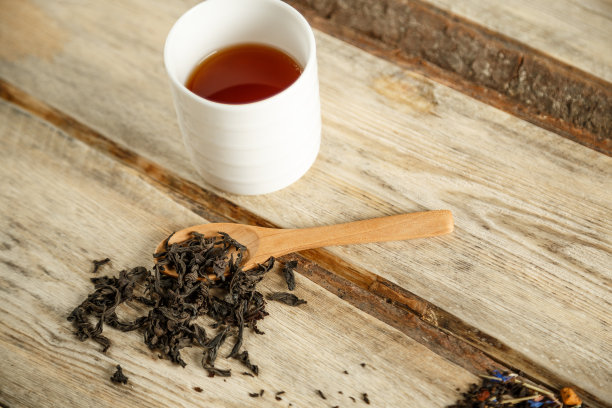 不同品种的天然茶在勺子和冲泡在一个木制背景的杯子。从上往下看图片下载