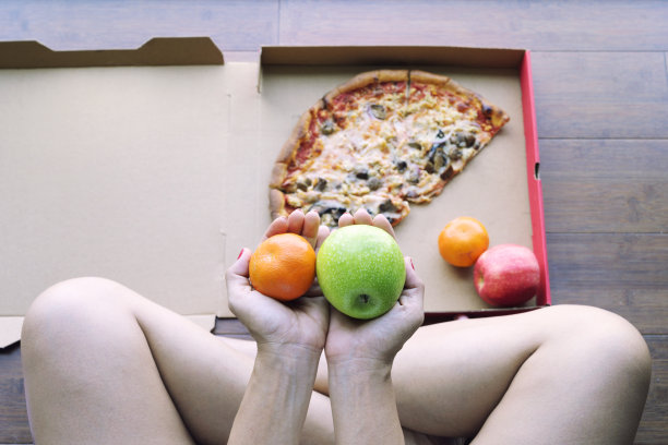 女人手中的苹果橙子与披萨背景图片下载