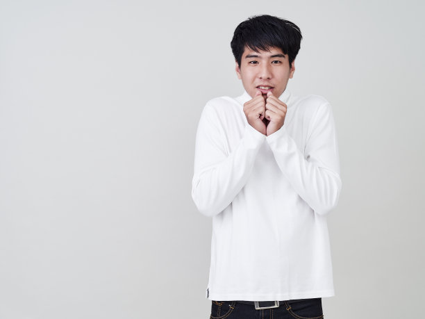 工作室肖像的年轻亚洲男子穿着白色的毛衣在白色的背景。图片下载