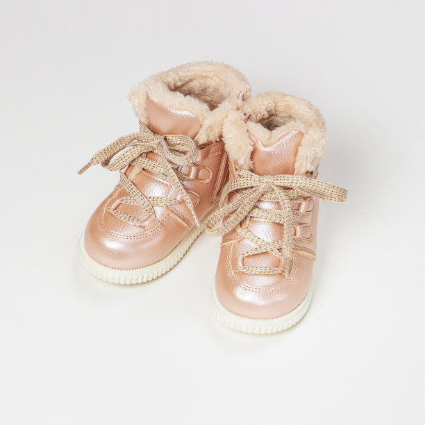 小的粉红色皮靴与毛皮带花边。白色背景上的温暖婴儿鞋。图片下载