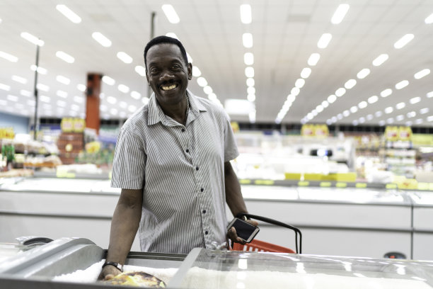 一个微笑的男人从超市冰箱里拿东西的照片图片下载