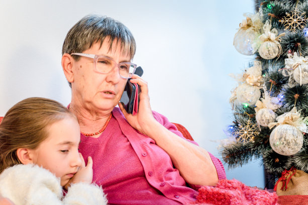 不开心，无聊的女孩坐在祖母旁边，她正在用手机图片下载