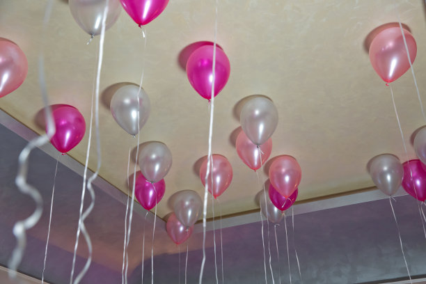 为了聚会，彩色的气球漂浮在房间的白色天花板上。婚礼或孩子生日聚会的室内装饰。氦气球图片下载
