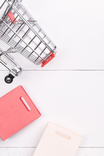 抽象的设计元素，年度销售，购物季节的概念，小手推车与彩色纸袋在白色木制桌子背景，俯视图，平铺图片下载