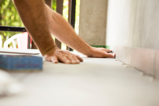 建筑工人用手把瓷砖粘在墙上。图片下载