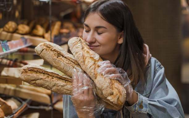 年轻女子在超市买新鲜面包。图片下载