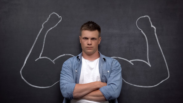 严肃的男人站在背景上，画着二头肌，健美图片下载