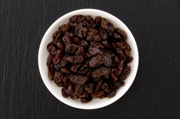 葡萄干在小盘黑石背景图片下载