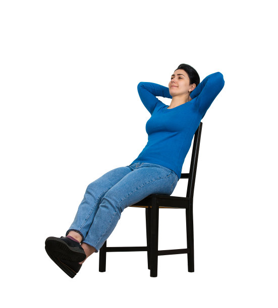 愉快的年轻女子放松在她的椅子上，享受自由时间隔离在白色的背景。全身像快乐的女孩梦想家坐舒适保持双手后的头。图片下载