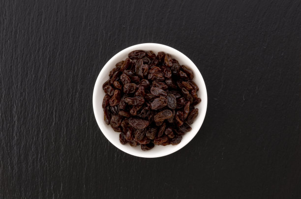 葡萄干在小盘黑石背景图片下载