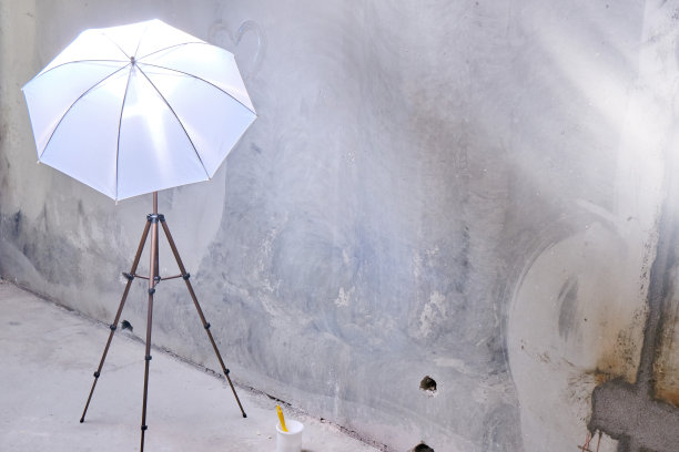 在阁楼风格的摄影工作室修复。未涂饰的光秃秃的墙壁可以刷漆了。白色油漆，三脚架和雨伞，闪光灯，照片配件。图片下载