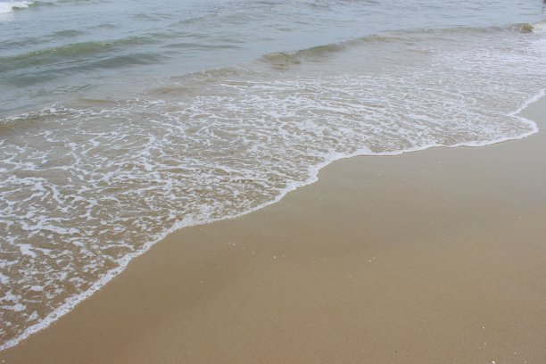 抽象的背景。带着泡沫的海浪拍打着沙滩墙纸图片下载