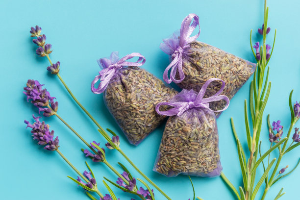 香袋或袋与干薰衣草花在蓝色的背景。薰衣草香袋旁的薰衣草小枝。图片下载