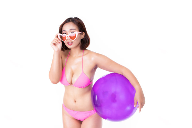 有吸引力的美丽的亚洲年轻女子在粉红色比基尼举行的夏季假期概念沙滩球孤立在白色的背景。图片下载