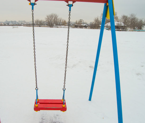 空荡的儿童秋千在雪地里，秋千上挂着铁链，供儿童在冬天娱乐图片下载