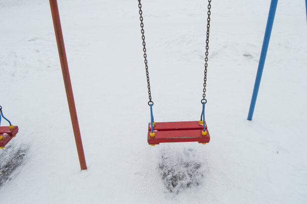空荡的儿童秋千在雪地里，秋千上挂着铁链，供儿童在冬天娱乐图片下载