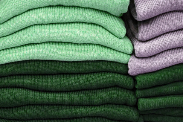 暖和的衣服整齐地叠在货架上。汗衫、毛衣、套头衫、开襟羊毛衫、帽衫、胸围帽都堆在架子上。衣服存储。尺寸范围。图片下载