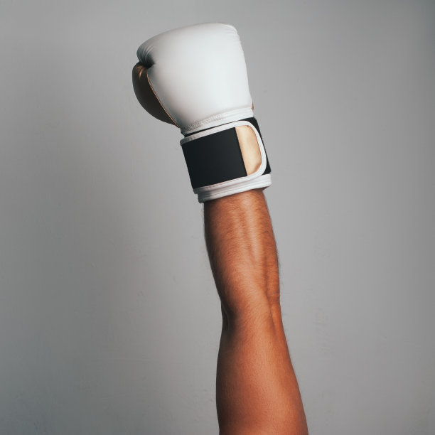 在灰色的背景上戴上白色的拳击手套。拳击手得意洋洋地举起手，图片下载
