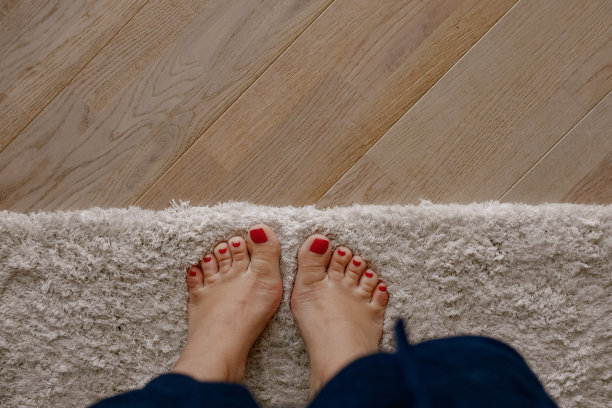 女人的脚踩在地毯和木质地板上图片下载