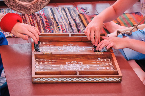 两个人玩的西洋双陆棋。手棋玩家在双陆棋上移动筹码。复古的中东风格的家具。图片下载