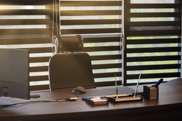 商业办公场所。阳光在工作场所为首席，老板或其他员工。桌子和舒适的椅子。光线透过半开的百叶窗图片下载